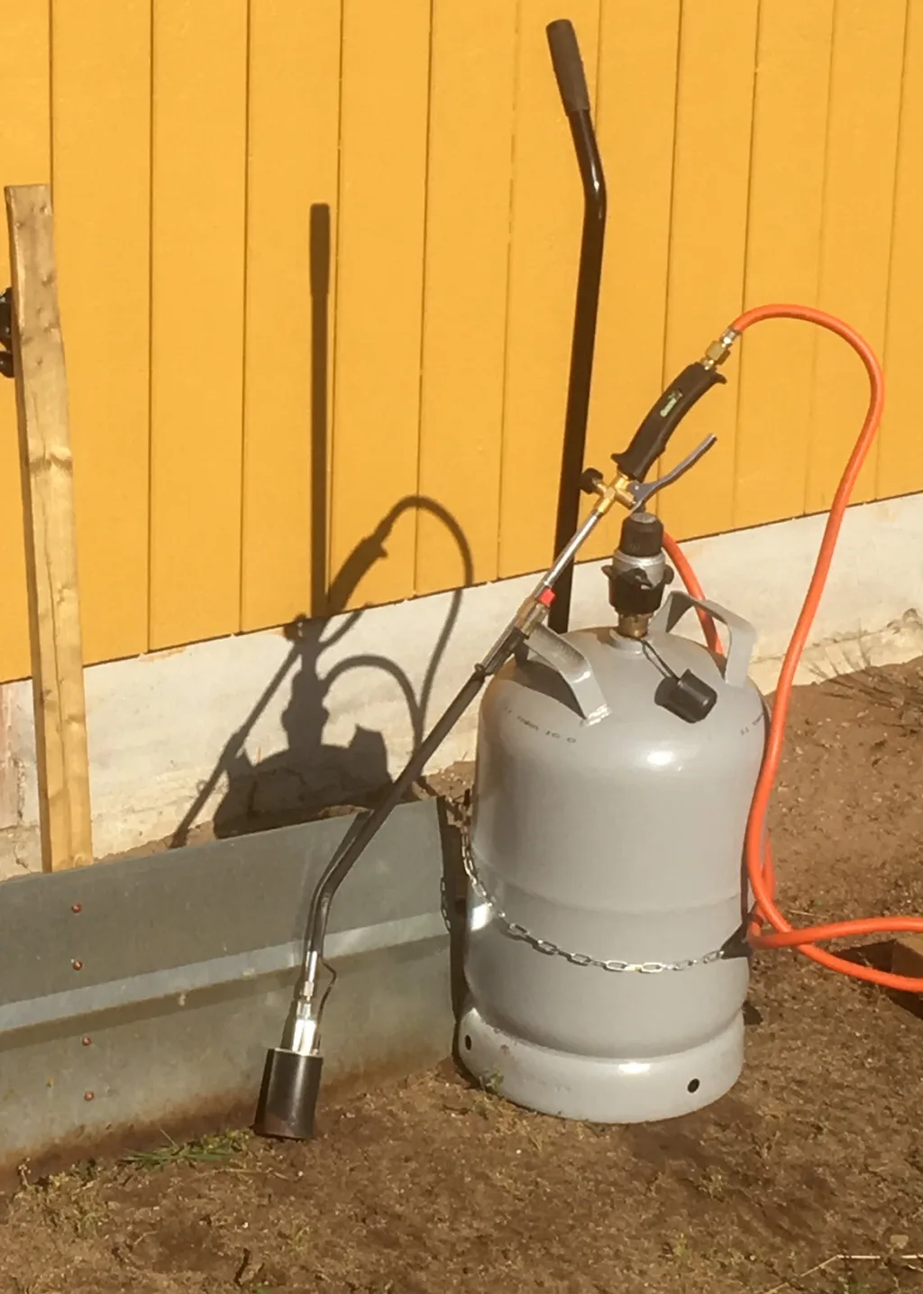 På flammeutstyret har Odd Arne montert på en skjerm 90x 30 cm. Denne brukes etter at gulrotplantene har kommet opp. Skjermen trykkes litt ned i jorda slik at flammene ikke slipper til på undersida. Men brenneren må bevege seg raskt, slik at varmen fra skjermen skader plantene