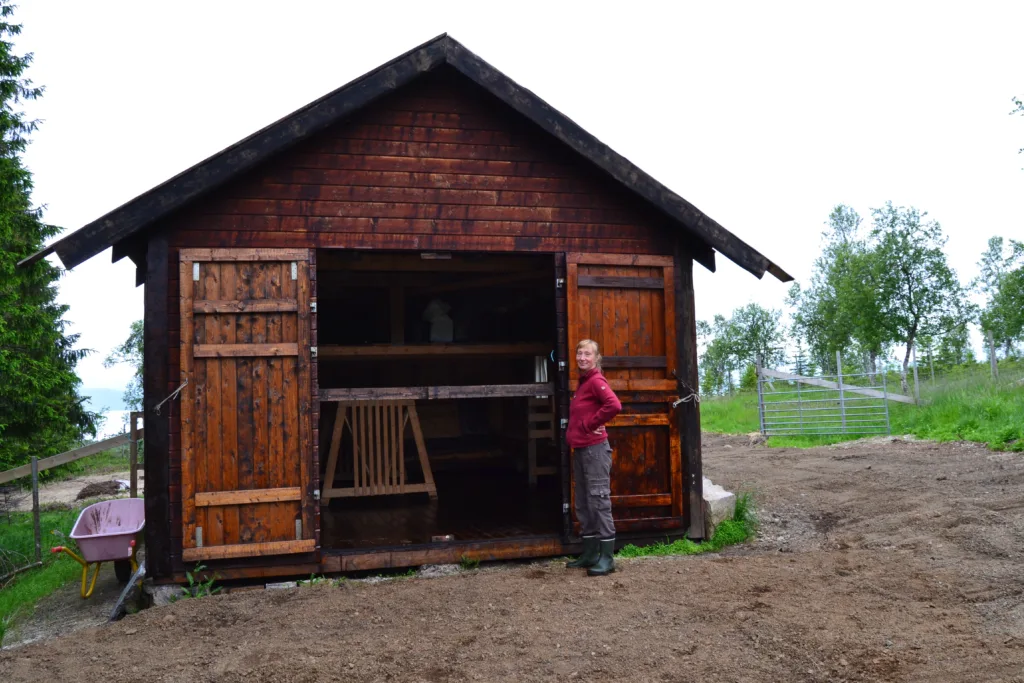 Anna ved et av de flyttbare småhusene som sauene kan bruke når været er ekstra ruskete.