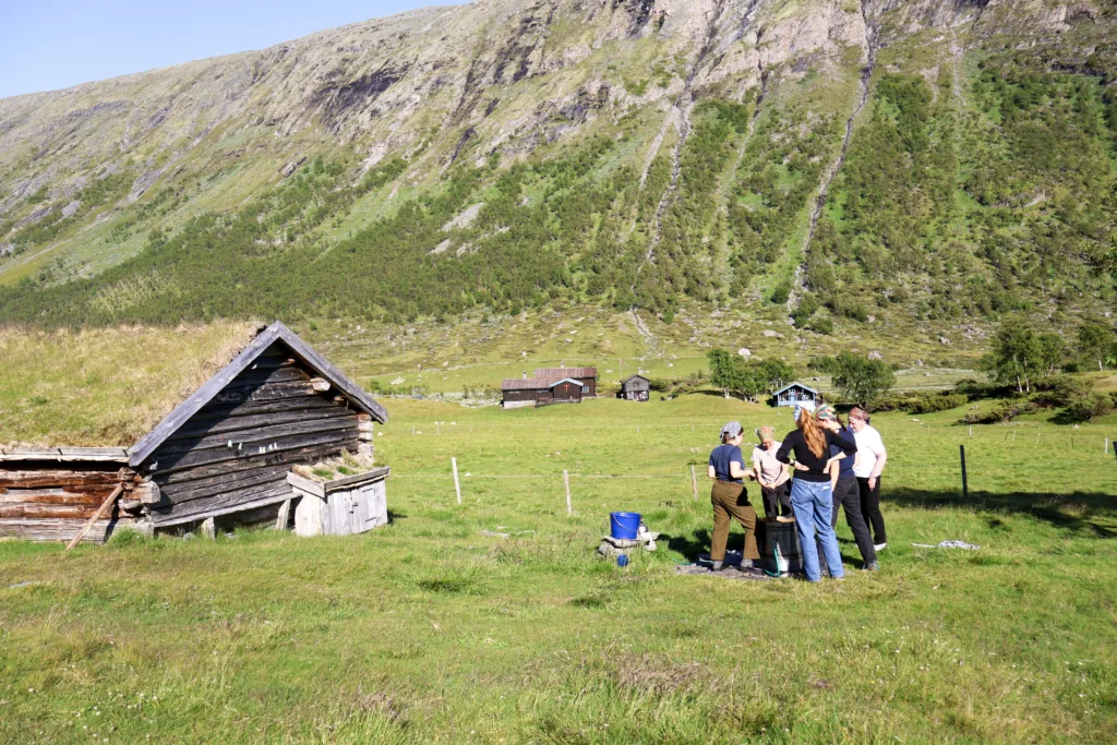 Kursdeltakerne samarbeider om å røre brunostmassen under avkjøling, en tung prosess der det er godt å være flere som bytter på