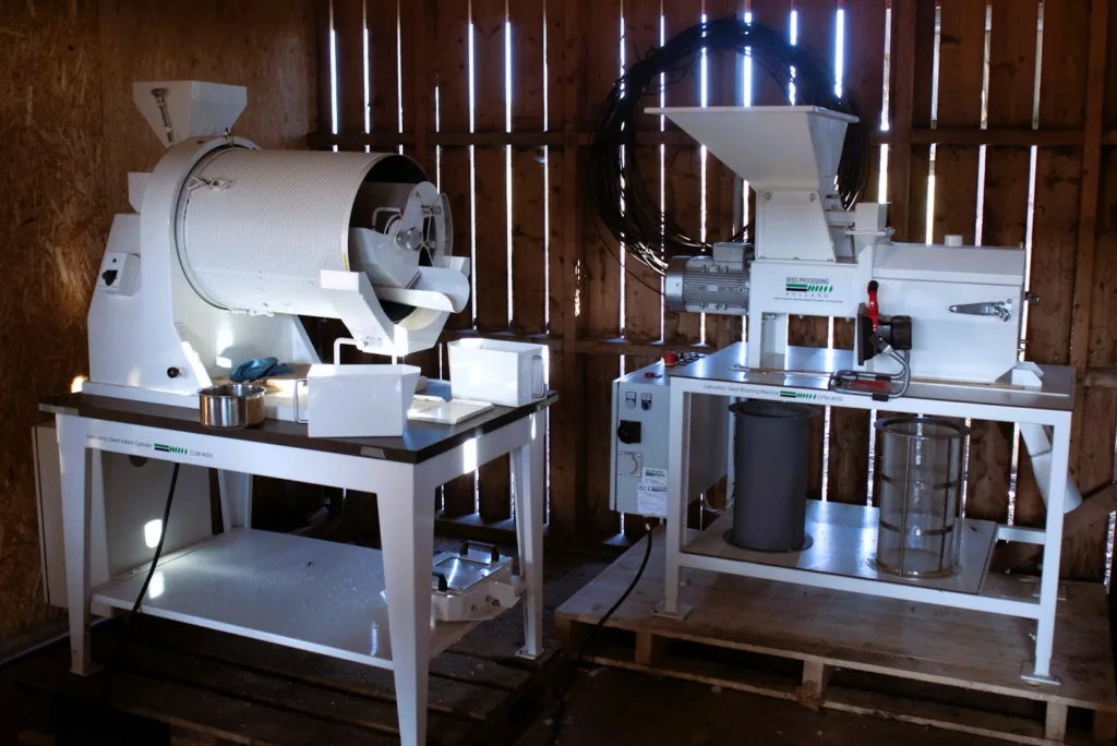 Maskinen til venstre kalles en sylindertriør, den kan skille frø fra planterester. Partiklenes lengde er utslagsgivende for prosessen. Solhatt bruker den blant annet til frø av rødbeter, pastinakk og gulrot. Maskinen til høyre er en frøbørstemaskin. Den brukes blant annet til å fjerne 'piggene' på gulrotfrø, men også til å polere tomat-, rødbet- og engblomstfrø