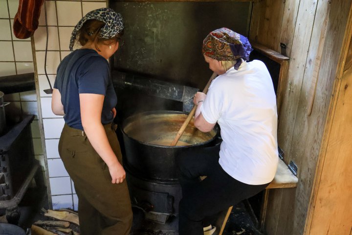 Kursdeltakerne lærer håndverket i praksis. Budeie Inger Marie følger med og sørger for at brunosten røres jevnt og ikke brenner seg